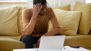 man zit achter laptop en is opgelicht via boilerrroomfraude - slachtoffer van oplichting
